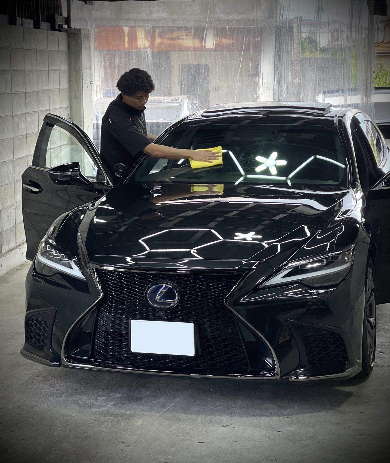 GARAGE ACEで黒いレクサスのガラスを施工するスタッフ