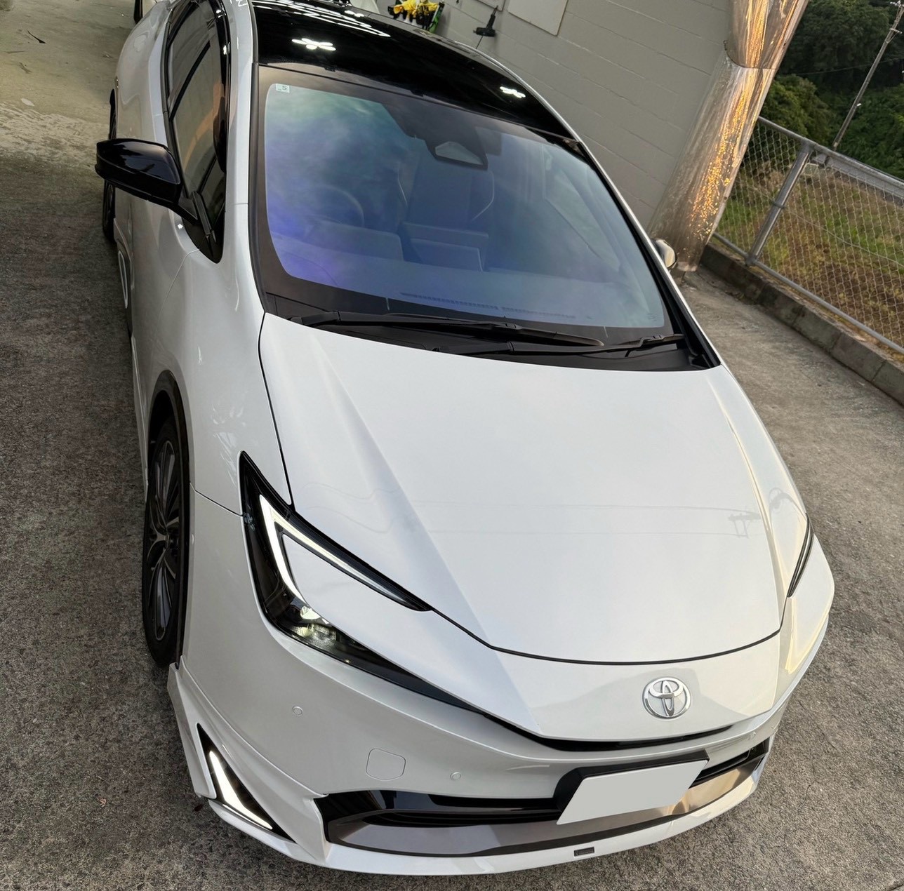 フロントガラスにカーフィルムを施工した白い車
